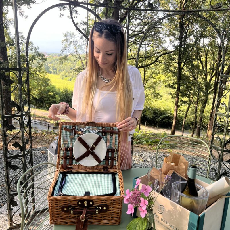 Ragazza con picnic con prodotti piemontesi sotto uccelliera di ferro nel bosco di Gavi