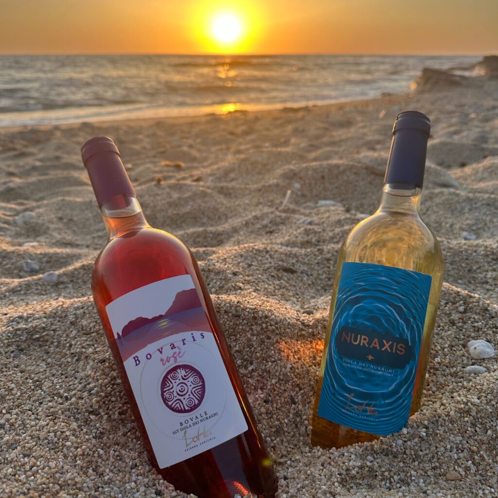 bottiglie di vino su una spiaggia sarda al tramonto