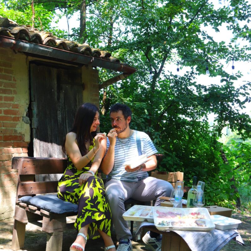 Persone che degustano una merenda sinoira in un bosco del Monferrato