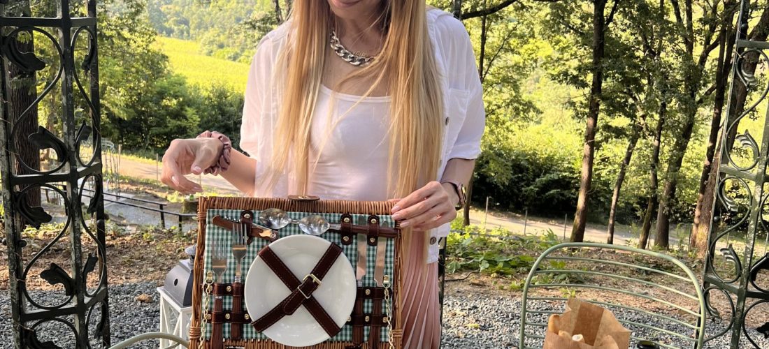 Ragazza con picnic con prodotti piemontesi sotto uccelliera di ferro nel bosco di Gavi