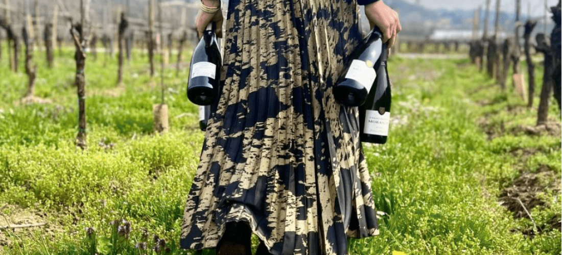 Ragazza che cammin in vigna tenendo in mano bottiglie di vino durante il Tour Bollicine "Tre Vini"